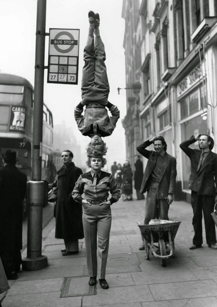 Two members of the Bertram Mills Circus walk head-to-head at Hammersmith Broadway in London, 1953